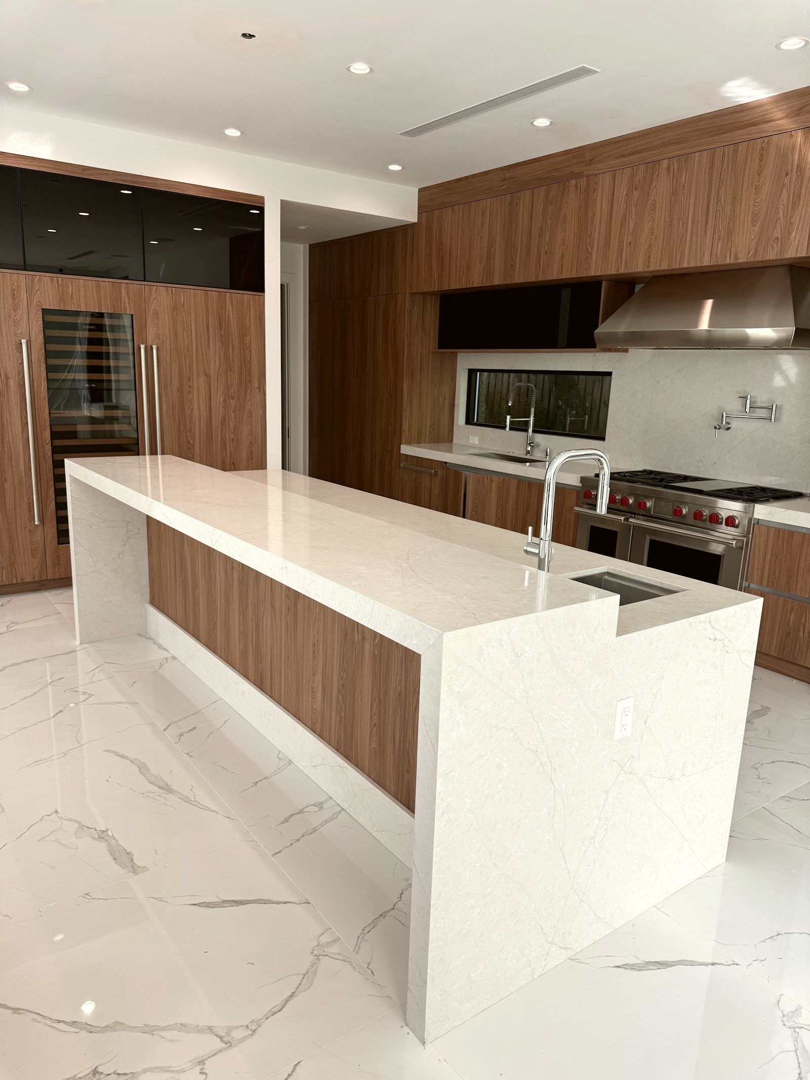 Quartz waterfall island with walnut cabinetry — real Miami kitchen