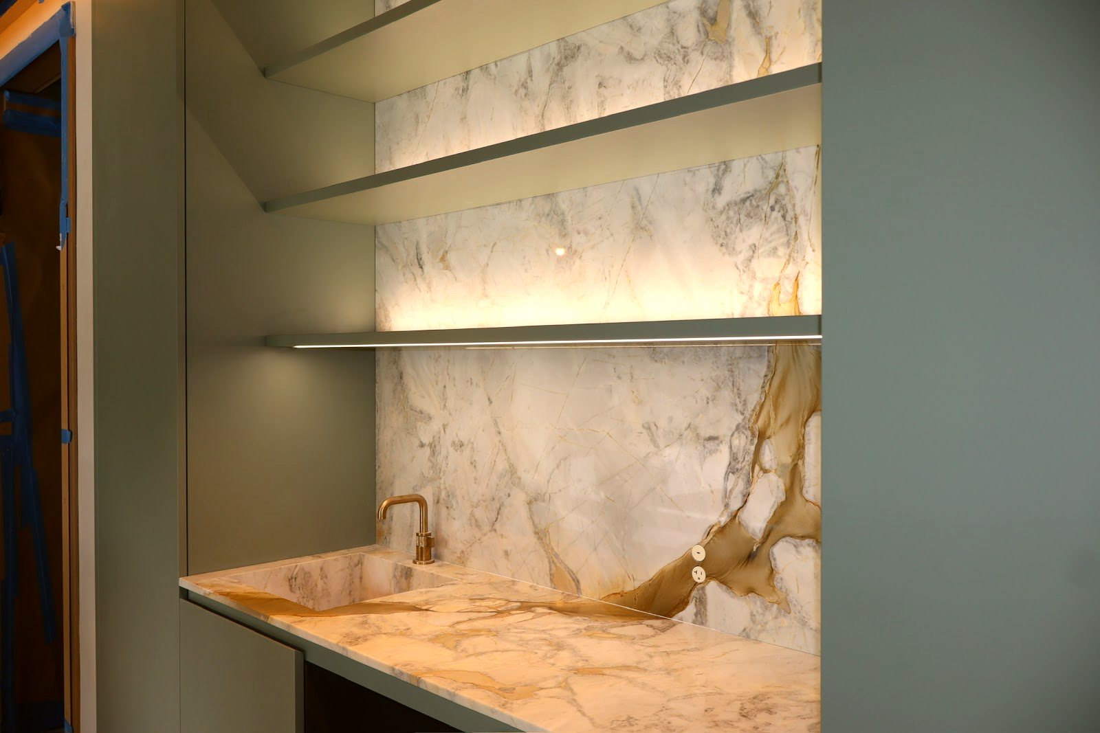 Gold-veined marble feature wall and shelf — real project